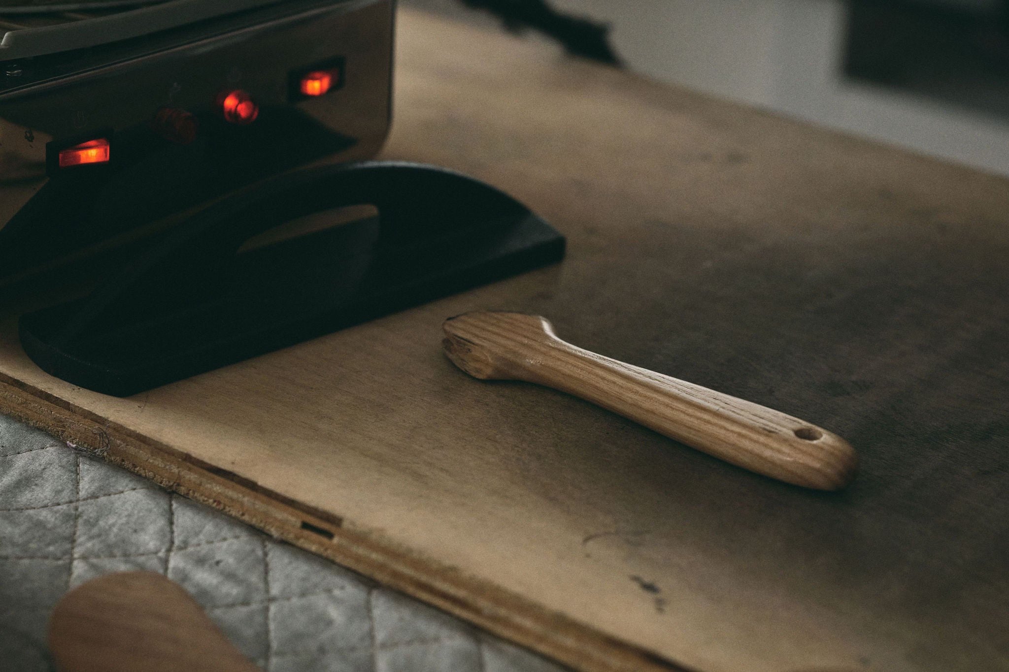 Black electronic device with red lights and a wooden tool on a wooden surface.